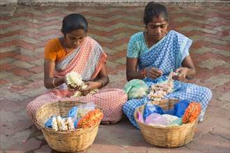 Two girls producing floral decorations to sell them later