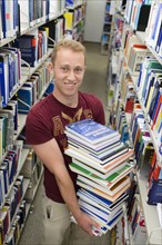 Student carrying a stack of books in the Departmental Library of the University of Hohenheim