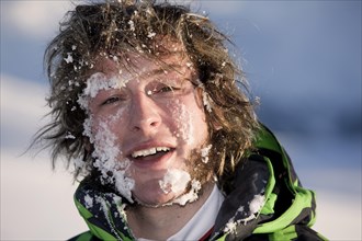 Young man with his face full of snow