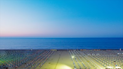 View of a beach with sunshades and sun beds at twilight