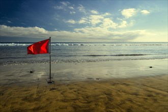 Red bathing prohibition flag standing on a beach