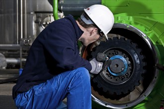 Technician attaching the connecting gear-wheel of an electric generator with an impact wrench