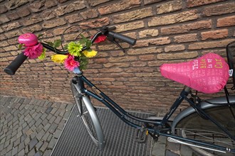 Bike decorated with flowers leaning against a wall