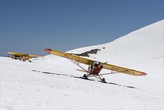 Yellow light aircrafts parking on a snowy slope on Moenchsjoch