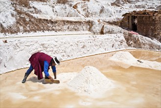 Locals piling up salt with a wooden board