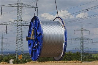 Loading a roll of conductive cable after work on a high-voltage transmission mast