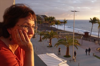 Woman looking from balcony over promenade of Puerto Naos