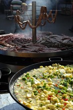 Large pan containing potato stew in front of giant barbecue at the annual All Saints Market in Cocentaina