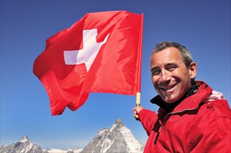 Tourist holding a Swiss flag over the Matterhorn