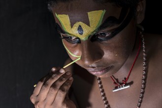 A Katakali artist is applying the make-up of the character Arjun for the Santhana Gopalam play during a temple festival