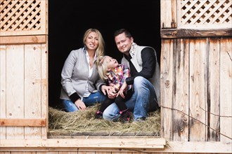 Young family sitting in the hay barn