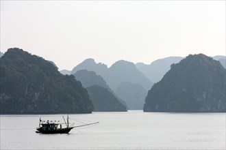 Fishing boat in front of limestone cliffs in Halong Bay