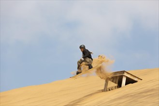 Sand boarding in the dunes of the Namib Desert