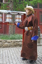Elderly man wearing a traditional deel while rotating prayer wheels in the Buddhist Gandan Monastery