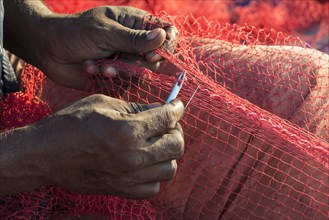 The hands of a fisherman repairing fishing nets