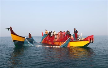 Local fishermen bringing in the nets onto their boat