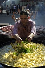 Cook adds pieces of green peppers to a large pan containing potato stew at the annual All Saints Market in Cocentaina