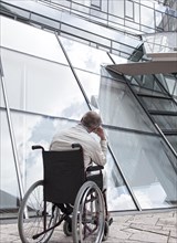 Elderly man sitting in a wheelchair in front of a modern building
