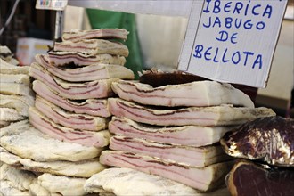 Slabs of bacon stacked in market stall at the annual All Saints Market in Cocentaina