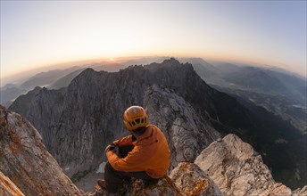 Climber sitting on the top of Ellmauer Halt at sunrise