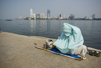 A Muslim woman wearing a burka is begging for money on the walkway