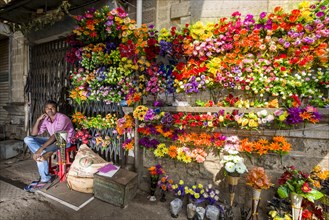 A street vendor is selling colorful artificial flowers