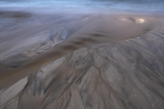 Water flows into the sea at the sandy beach