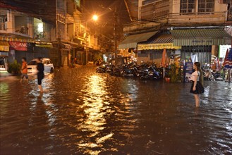 Street scene with a flooded road during heavy monsoon rain at night