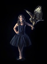 Girl wearing a black ballet dress with a bird of prey on her arm