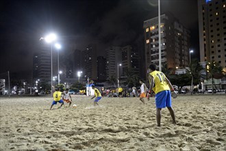 Young people playing football in the evening at the beach