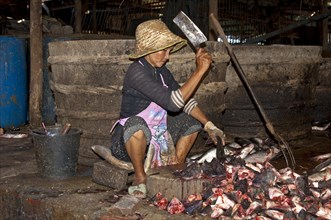 Woman chopping fish at the fish market