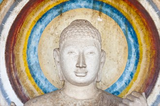 Head of a Buddha figure surrounded by a nimbus in rainbow colors