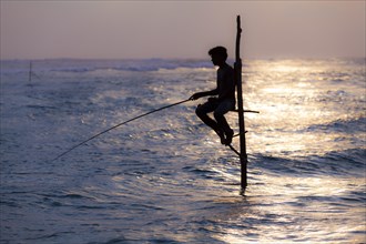 Stilt fisherman fishing in shallow water