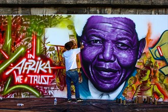 Graffiti artists standing in front of a graffiti of Nelson Mandela