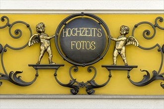 Wrought iron sign for 'Hochzeitsfotos' or wedding photos with cherubs on a photo shop