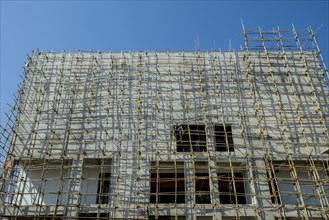 A construction site of a new concrete building with bamboo scaffolding attached