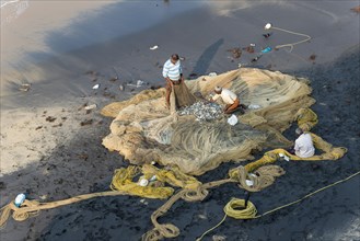Fishermen inspecting fishing nets on the beach