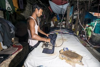 A labourer is ironing laundry at Mahalaxmi Dhobi Ghat
