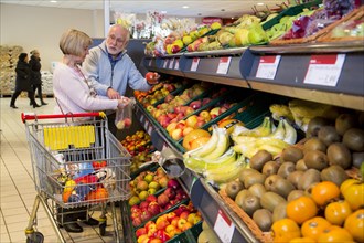 Senior couple shopping with a shopping trolley in the fruit and vegetables department of a supermarket