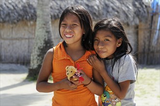 Two Kuna Indian girls holding a small soft toy