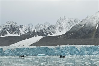 Tourists in rubber dinghies in front of the rim of the Monacobreen Glacier