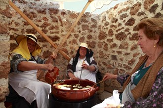 Elderly women in traditional costume baking 'bunyols'