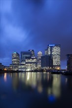 Skyline of the financial district Canary Wharf with the Blackwall Basin at the front at dusk