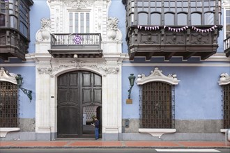 Street scene of man reading in front of the colonial facade of Casa de Osambela