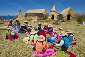 Women of the Uro Indians sit in front of typical reed huts