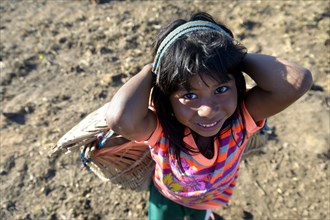 Girl carrying a traditional basket on her back in a village of the Xavantes people