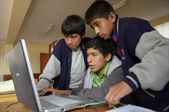 Three boys in a children's home are working together on a laptop