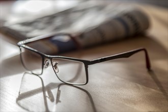 Glasses lying in front of a daily newspaper