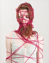 Woman constrained with pink cotton yarn