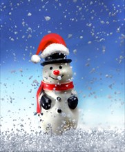 Snowman figure with a Santa Claus hat in the snow